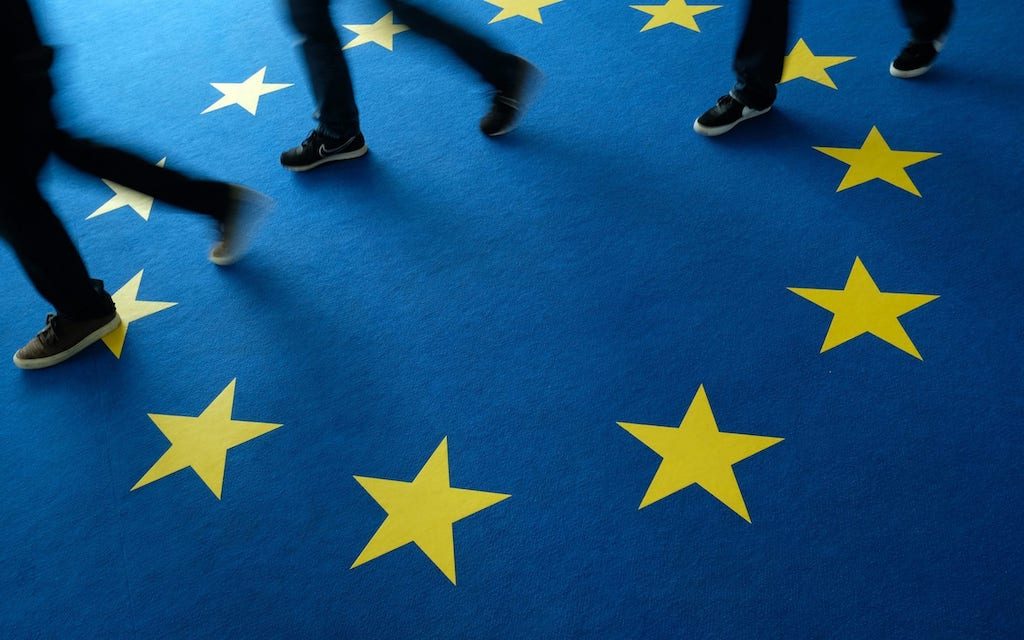 People walking across a printed European Union flag